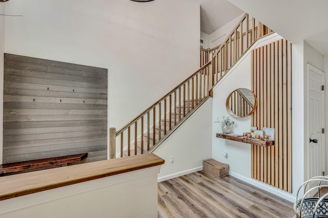 staircase with a high ceiling, baseboards, and wood finished floors