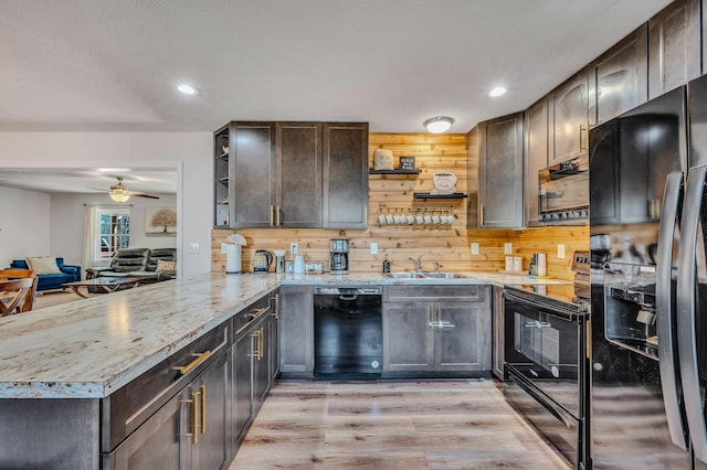 kitchen featuring dark brown cabinets, a peninsula, black appliances, and a sink