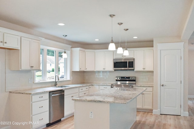 kitchen featuring stainless steel appliances, light wood-type flooring, a center island, and white cabinets