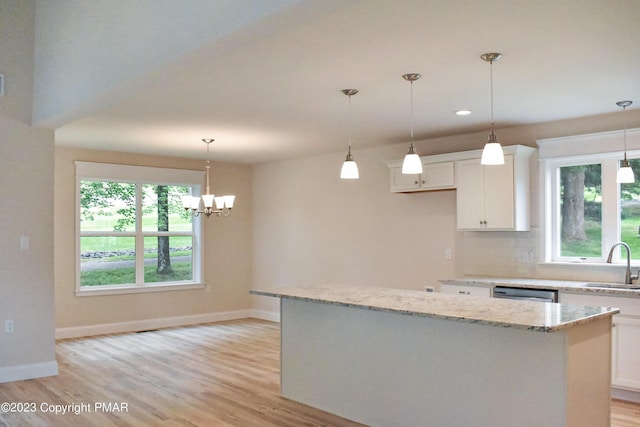 kitchen featuring tasteful backsplash, white cabinets, a sink, and light wood-style flooring