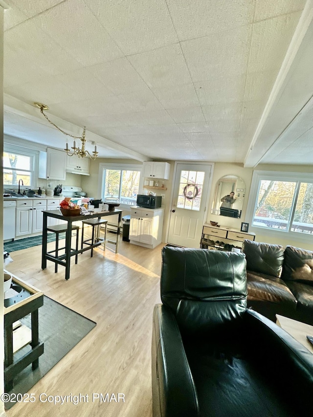 living area featuring light wood-style flooring and an inviting chandelier