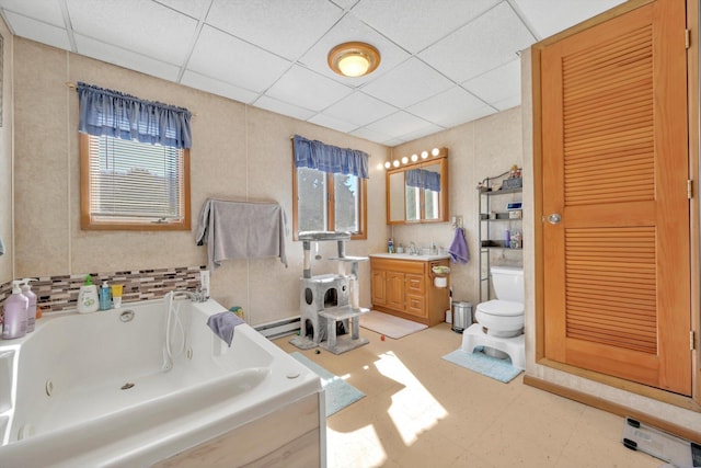 full bath featuring a drop ceiling, toilet, a whirlpool tub, baseboard heating, and vanity