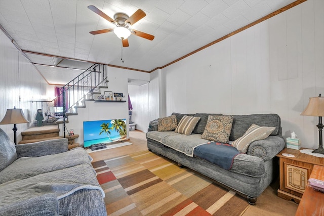 carpeted living room with a ceiling fan and stairs