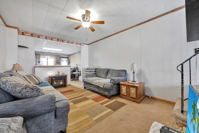 carpeted living room with a glass covered fireplace, baseboards, crown molding, and a ceiling fan