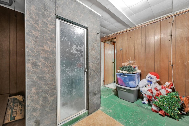 interior space featuring a shower stall and wood walls