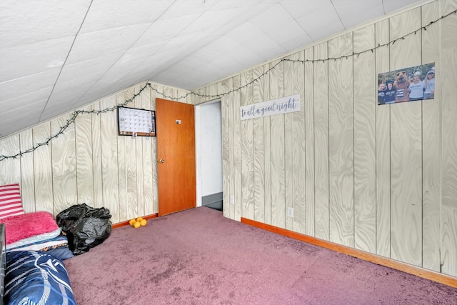 bonus room featuring baseboards, carpet, wooden walls, and vaulted ceiling