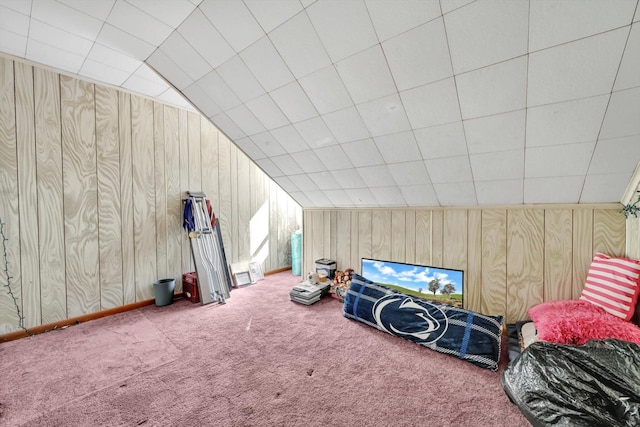 interior space with carpet floors, wood walls, and vaulted ceiling