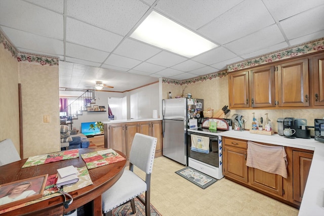 kitchen featuring electric stove, freestanding refrigerator, brown cabinetry, light countertops, and light floors