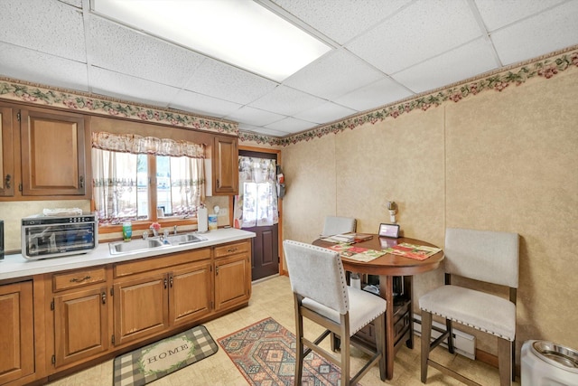 kitchen with light countertops, a drop ceiling, and a sink