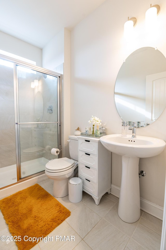 bathroom with a shower stall, tile patterned flooring, baseboards, and toilet