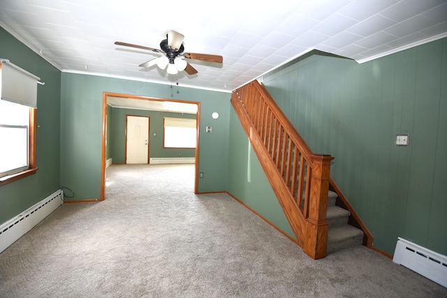 carpeted empty room featuring a baseboard heating unit, stairway, and a ceiling fan