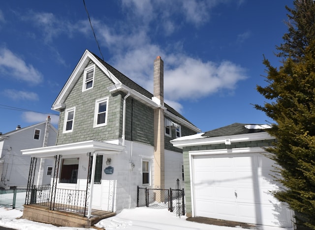 view of front of home with an outbuilding, covered porch, a garage, fence, and a chimney