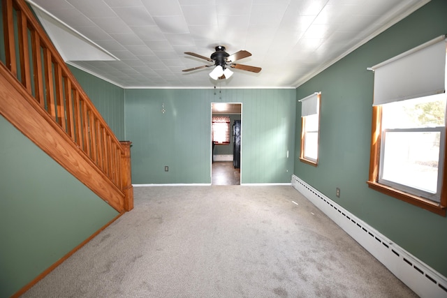 carpeted empty room featuring baseboards, a ceiling fan, a baseboard radiator, stairway, and ornamental molding