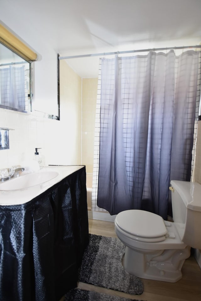 bathroom with tile walls, decorative backsplash, toilet, vanity, and wood finished floors