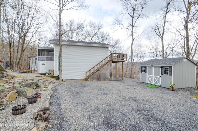 view of side of home with a sunroom, stairway, a storage unit, a deck, and an outdoor structure