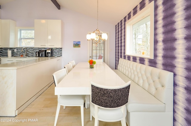 dining space featuring light wood-style floors, a notable chandelier, and lofted ceiling with beams