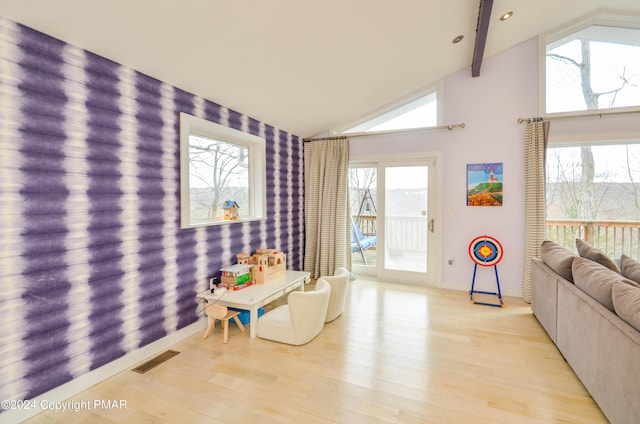 playroom featuring wallpapered walls, visible vents, lofted ceiling with beams, an accent wall, and light wood-type flooring