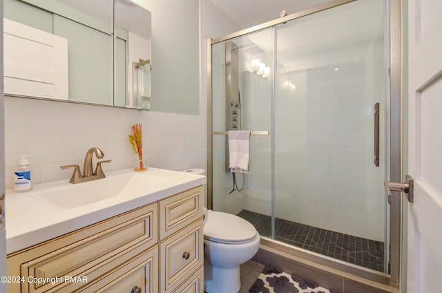 bathroom featuring toilet, a stall shower, and vanity