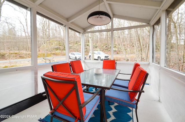 sunroom / solarium featuring vaulted ceiling with beams