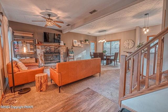 living area featuring visible vents, a textured ceiling, wood finished floors, a fireplace, and stairs