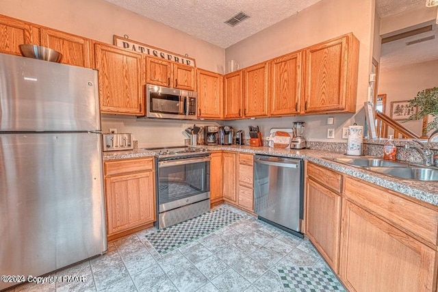 kitchen with visible vents, a sink, a textured ceiling, stainless steel appliances, and light countertops