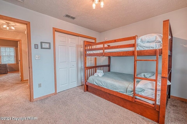 unfurnished bedroom with visible vents, baseboards, carpet flooring, a closet, and a textured ceiling