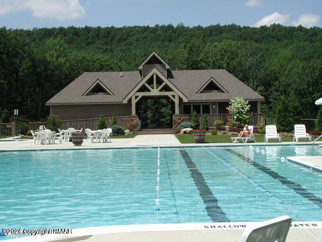 pool featuring a view of trees and a patio area