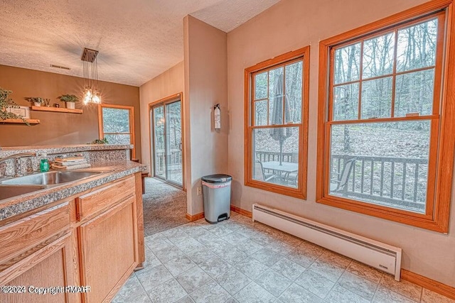 kitchen with a healthy amount of sunlight, a textured ceiling, a baseboard heating unit, and baseboards