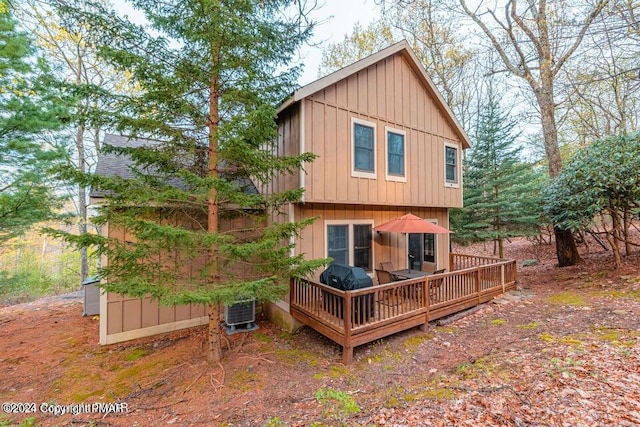 rear view of house with central AC unit, board and batten siding, and a wooden deck