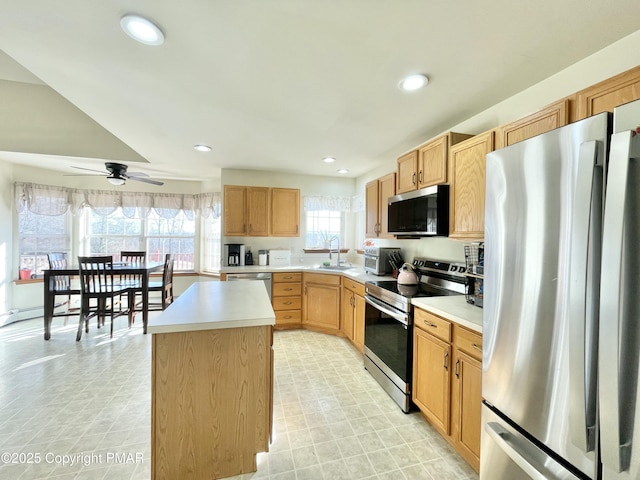 kitchen featuring ceiling fan, stainless steel appliances, sink, and a kitchen island