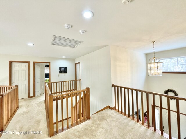 corridor with a chandelier and light carpet