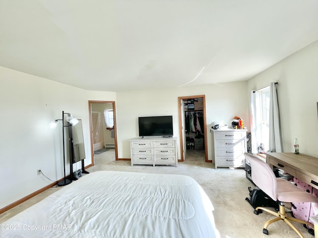 carpeted bedroom with connected bathroom, a spacious closet, a baseboard radiator, and a closet