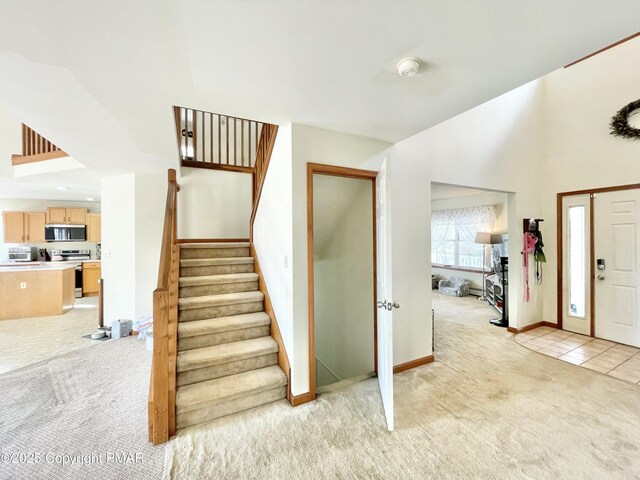 foyer entrance with a high ceiling and light colored carpet