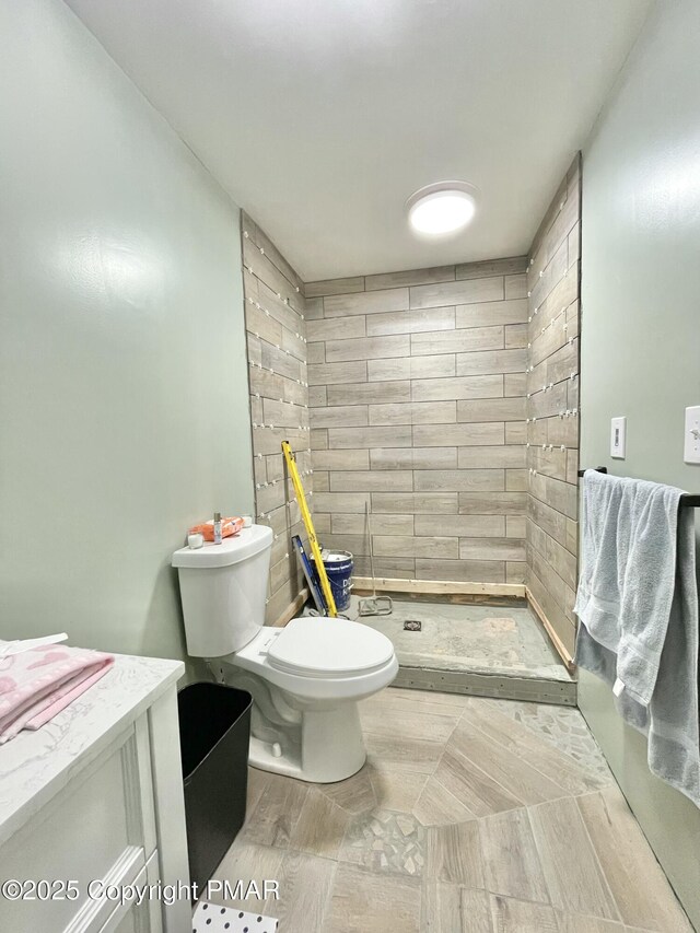 bathroom with vanity, a tile shower, and toilet