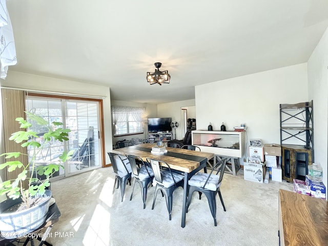 dining space featuring light carpet and a chandelier