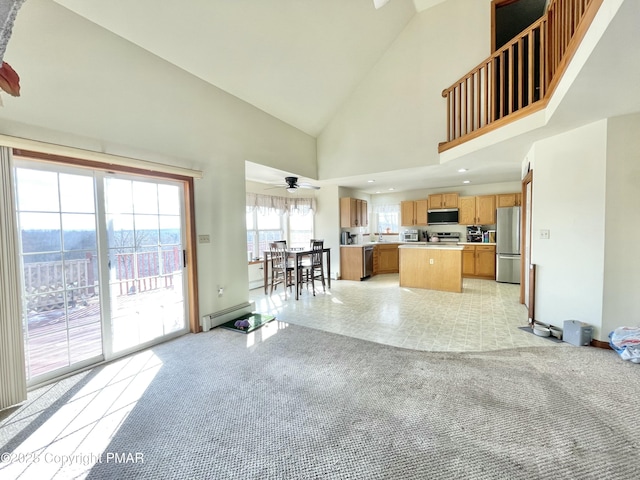 unfurnished living room with baseboard heating, ceiling fan, high vaulted ceiling, and light carpet