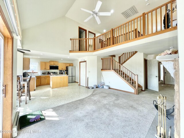 carpeted living room with ceiling fan and high vaulted ceiling