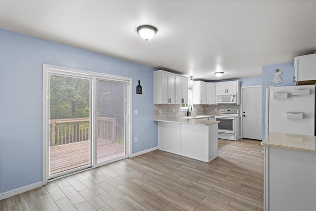 2615 Vista Dr, Blakeslee, PA 18610 - kitchen with white appliances, a peninsula, decorative backsplash, white cabinetry, and light wood-style flooring