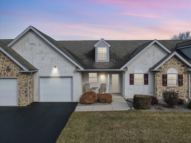 view of front of house with a garage, stone siding, driveway, and stucco siding