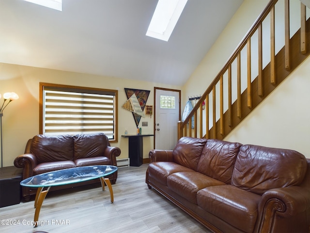 living area featuring light wood finished floors, lofted ceiling with skylight, a baseboard radiator, and stairway