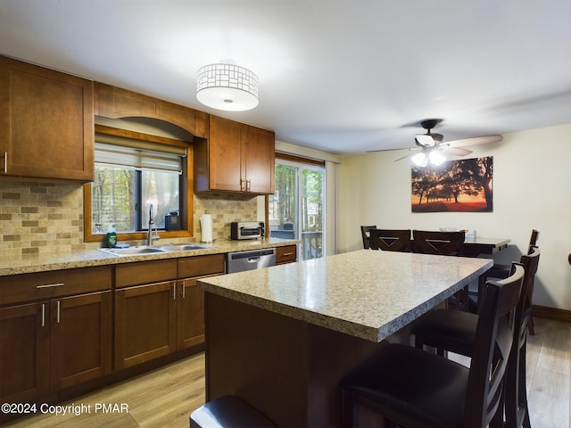 kitchen featuring light wood-style floors, dishwasher, a sink, and a breakfast bar area