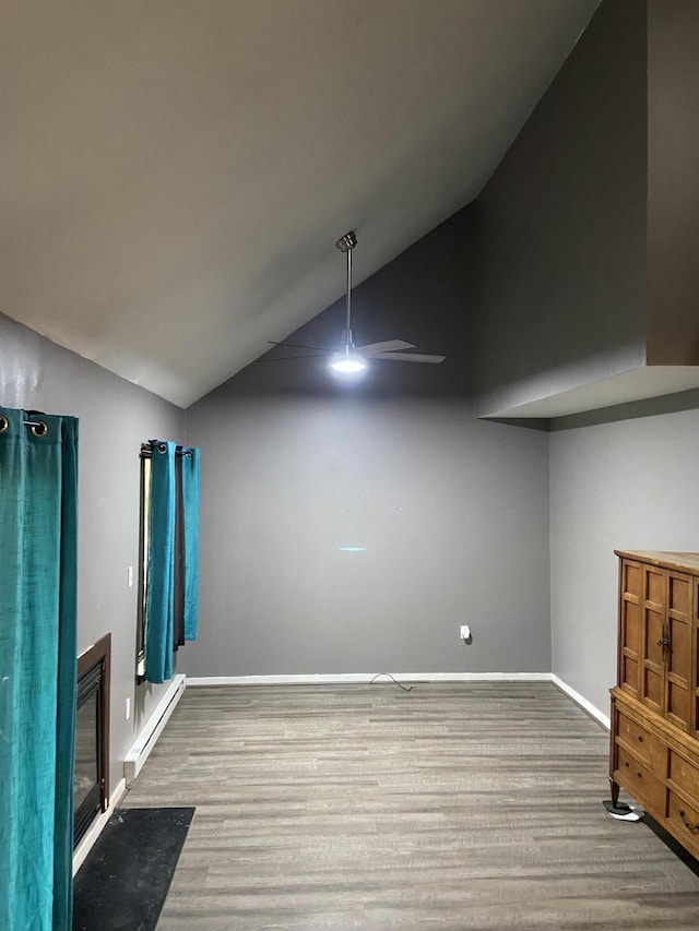 328 Crewe Ct, Bushkill, PA 18324 - unfurnished living room featuring a baseboard heating unit, wood finished floors, vaulted ceiling, baseboards, and a fireplace with flush hearth