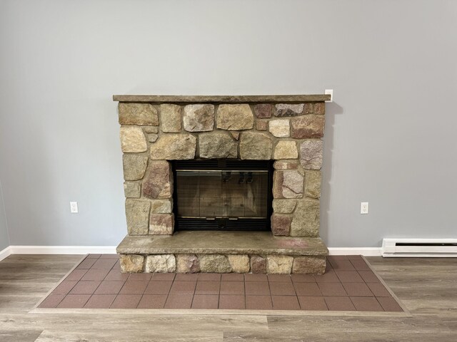 1223 Coolbaugh Rd, East Stroudsburg, PA 18302 - detailed view of a baseboard radiator, a stone fireplace, wood finished floors, and baseboards