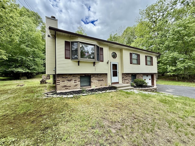 1223 Coolbaugh Rd, East Stroudsburg, PA 18302 - split foyer home featuring a chimney, asphalt driveway, a garage, and a front lawn
