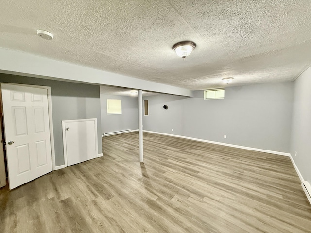 1223 Coolbaugh Rd, East Stroudsburg, PA 18302 - below grade area with a baseboard radiator, light wood-style floors, baseboards, and a textured ceiling
