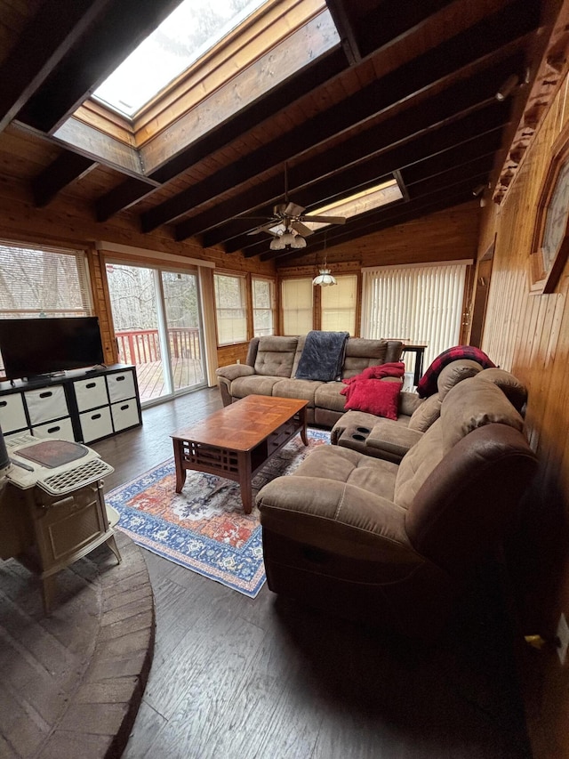 living area featuring a ceiling fan, lofted ceiling with skylight, wood finished floors, and wood walls