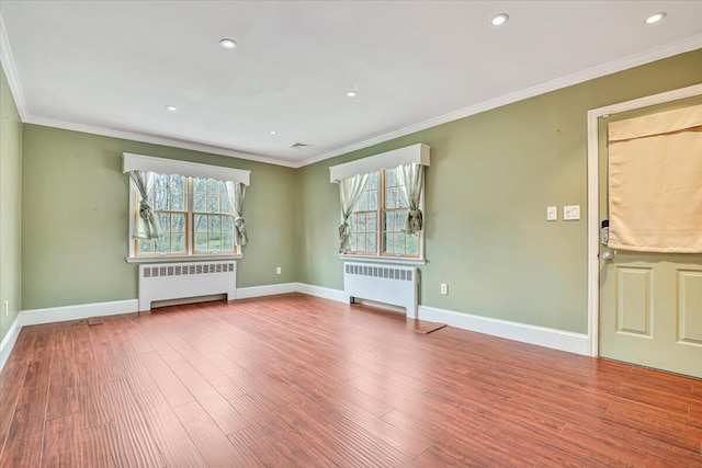 empty room featuring radiator, wood finished floors, and a healthy amount of sunlight