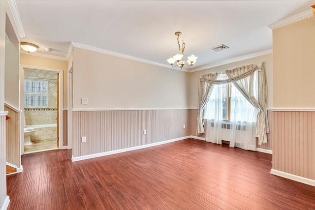 interior space featuring wood finished floors, an inviting chandelier, wainscoting, visible vents, and crown molding