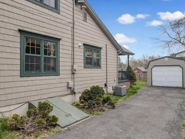 view of side of home featuring cooling unit, driveway, a garage, and an outbuilding