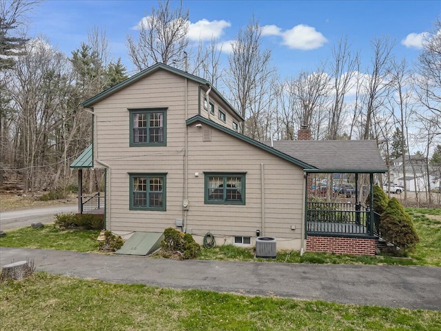 view of property exterior featuring a chimney, cooling unit, and covered porch